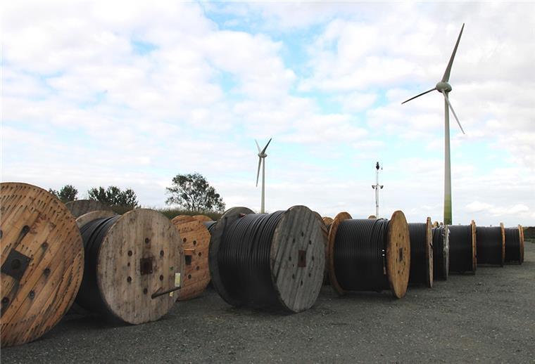 Kabel für den Stromtransport liegen vor zwei Windrädern