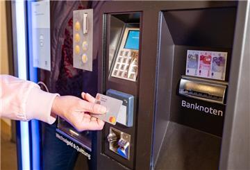 Eine Frau hält ihre Bankkarte an den Bezahlautomaten in einem Parkhaus.