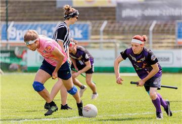 Spieler der "Hannover Niffler" (lila, SV Arminia Hannover) und "Broomicorns" (pink, Tura 1865 Braunschweig) in Aktion auf dem Spielfeld. Quidditch ist ein Kontaktsport, der in gemischtgeschlechtlichen Teams gespielt wird und Elemente aus verschiedenen Ballsportarten miteinander vereint. 