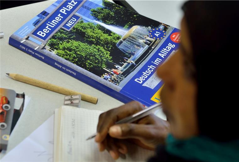Das Lehrbuch "Deutsch im Alltag" liegt in einem Deutschkurs für Flüchtlinge vor einer jungen Frau auf der Schulbank.