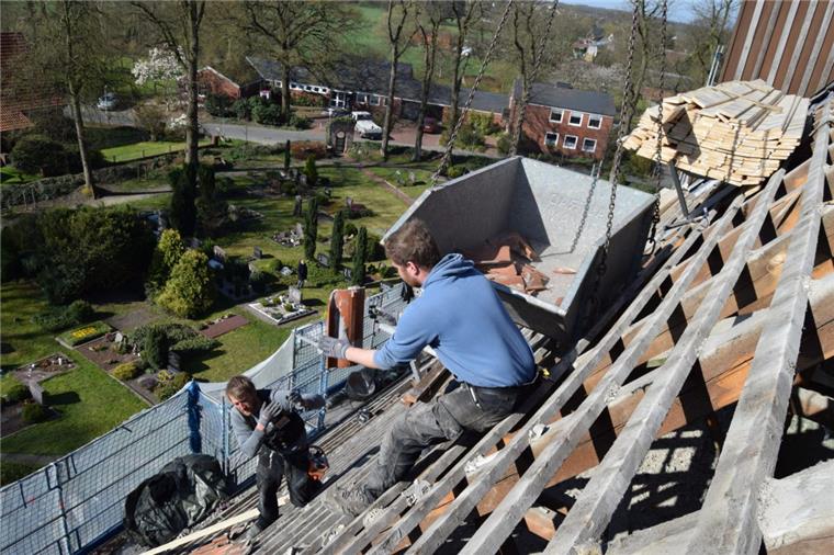 Handwerker steigen Debstedter Kirche aufs Dach St. Dionysius wird abgedeckt: Hanke Stürcken wirft die Dachziegel einzeln nach oben, Kollege Malte Meyer fängt sie auf und schmeißt sie in die stählerne Wanne, die der Kran nach oben gehievt hat.