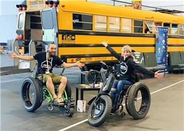 Stefanie Hoyer und Benjamin Hermann aus Nartum posieren in Rollstühlen vor ihrem zum Wohnmobil umgebauten US-Schulbus.