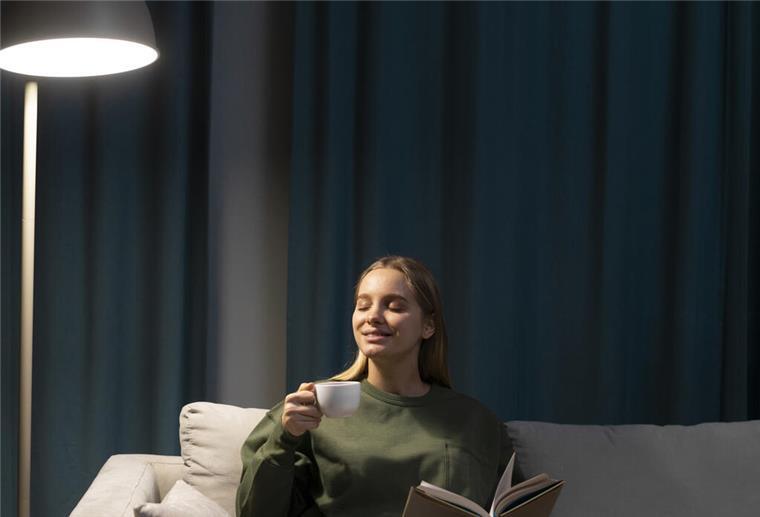 Frau sitzt auf Sofa und liest.
