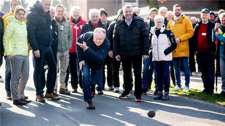 Ministerpräsident boßelt in Ostfriesland Stephan Weil (SPD), Ministerpräsident von Niedersachsen, wirft eine Boßelkugel über die Straße.