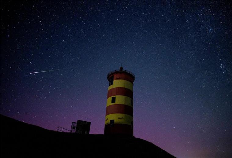 Himmels-Show im August! Sternschnuppen-Feuerwerk und Planetentreffen stehen an Eine Sternschnuppe leuchtet über der Nordsee am Nachthimmel über dem Pilsumer Leuchtturm.
