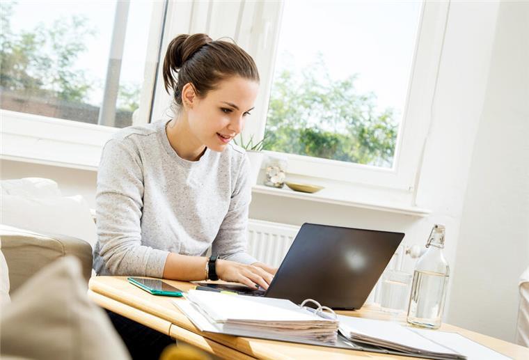 Gleiches Gehalt, aber weniger auf dem Konto? – Darum schwankt dein Netto Eine Frau sitzt am Laptop.