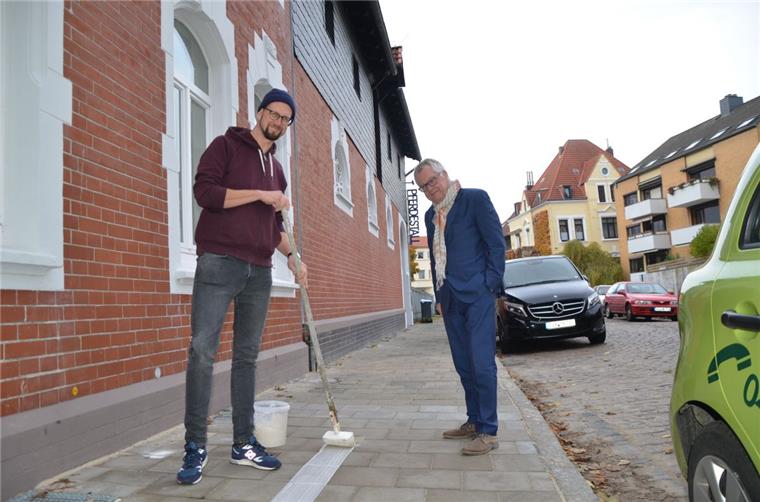 Künstler pinselt weißen Strich durch Bremerhaven Stipendiat Sebastian Dannenberg (links) beginnt mit dem Streifen auf dem Bürgersteig vor der Künstlerwohnung in der Gartenstraße. Klaus Becké bewundert dabei seine ruhige Hand.