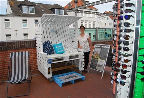 Strandkorb und Liege für Wartende, Sonnenbrillen und mehr für Touristen: Geschäftsleiterin Ina Niestaedt vor dem Info-Pavillon an der Kaje, der sein Angebot ergänzt hat.