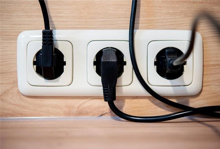 Die Netzstecker mehrerer Küchengeräte stecken in einer Steckdose an einer Küchenzeile.