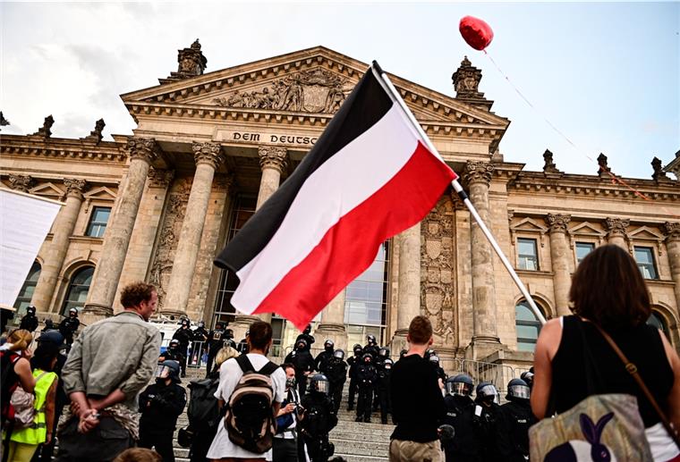 Empörung über Rechte vor dem Reichstag Teilnehmer einer Kundgebung gegen die Corona-Maßnahmen stehen vor dem Reichstag, ein Teilnehmer hält eine Reichsflagge.