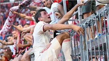 Thomas Müller steigt nach dem Bayern-Sieg auf den Zaun zu den Fans.