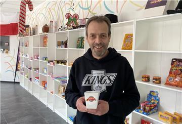 Ein Mann steht in einem Laden und hält eine Packung Eis in der Hand.