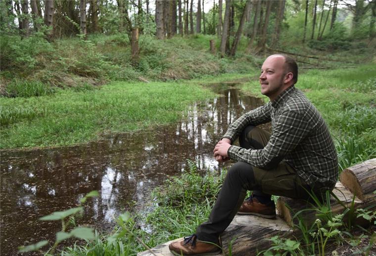Den Jagdschein für mehr Wissen über Natur und Umwelt Das Foto zeigt Thorben Rievesehl an einem Teich im Wald sitzend.