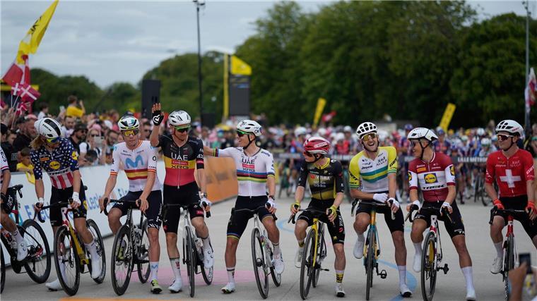 Titelverteidiger Tadej Pogacar (M) und andere Fahrer vor der Auftaktetappe der 112. Tour de France.
