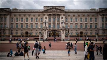 Touristen stehen vor den Toren vom Buckingham Palast in London.