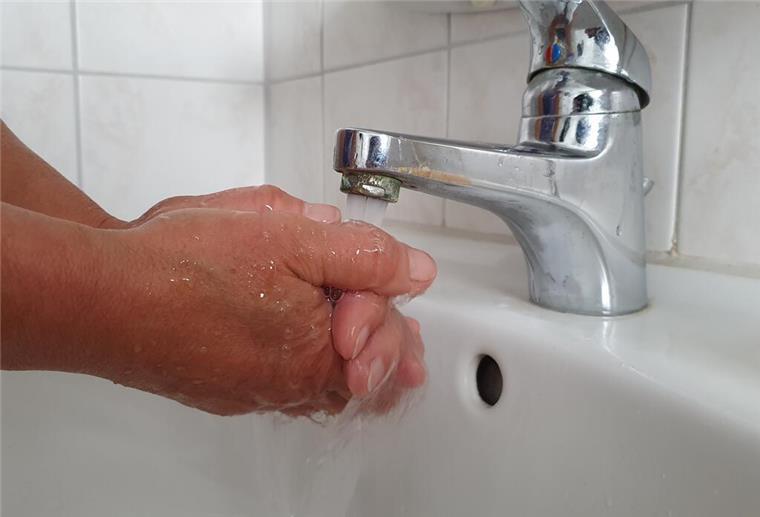 Hände werden unter laufendem Wasser aus einem Wasserhahn gewaschen