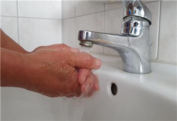 Hände werden unter laufendem Wasser aus einem Wasserhahn gewaschen