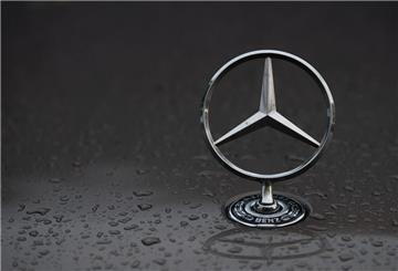 Regentropfen sind auf einem Mercedes-Stern auf einem Fahrzeug zu sehen.