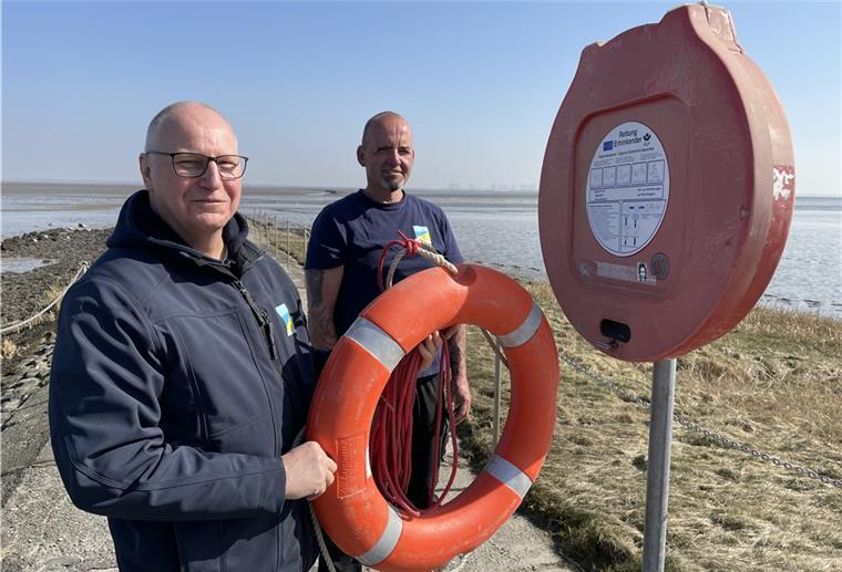 TSB-Außenbereichsleiter Reiner Jahn (links) und sein Kollege Thomas Petz bestücken den Kasten auf der Schlenge in Burhave wieder mit dem Rettungsring, der dort hineingehört. Im Winter wird er herausgenommen, um nicht Vandalismus Vorschub zu leisten.