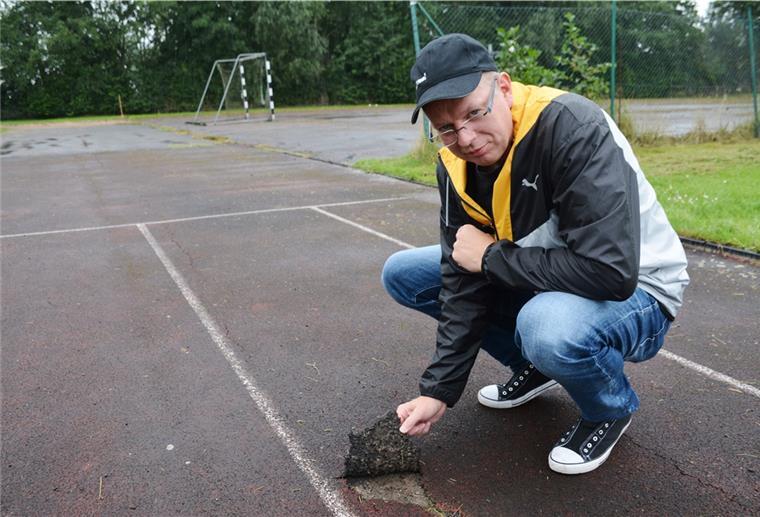 Tossens: Bei Sportplatz-Sanierung ist Ausdauer gefragt TuS-Vorsitzender Renke Hesenius zeigt, dass sich lösender Tartanbelag die Nutzung der Kunststoffbahn unmöglich macht.