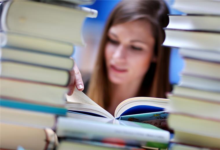 Cuxhavener Stadtbibliothek: Ukrainische Bücher für Geflüchtete Eine junge Frau liest an einem Tisch voller Bücher