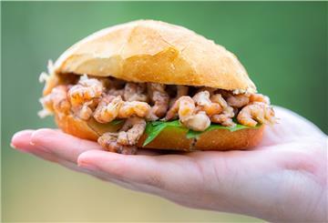 Die Erfinderin einer neuen Krabbenpultechnik steht mit einem Krabbenbrötchen in der Hand vor der Kamera.
