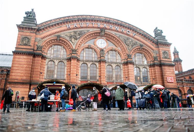 Zahlreiche bedürftige Menschen stehen an Heiligabend in einer Schlange vor dem Kältebus der Johanniter auf dem Vorplatz am Hauptbahnhof.