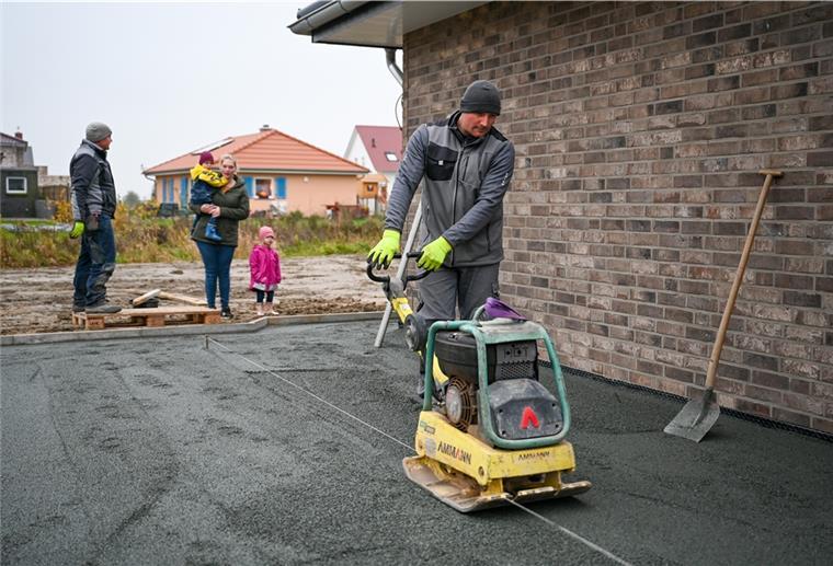 Unser Traumhaus: Die Pflasterung kommt ums Haus Bauarbeiter richtet eine Fläche mit einem Arbeitsgerät.