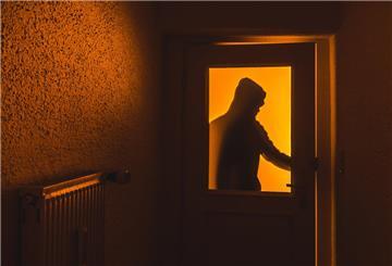 Die Silhouette eines Mannes mit Kapuze ist hinter einer Scheibe zu sehen. 