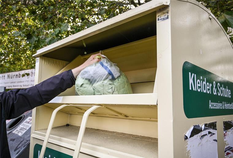 Hundewelpe aus Altkleidercontainer gerettet: Feuerwehr im Einsatz Ein Mann wirft einen Kleidersack in einen Altkleider-Container am 11. September 2024 in Bonn...Zum KNA-Text "Wie eine Schneiderin liebgewonnene Erbstücke repariert"