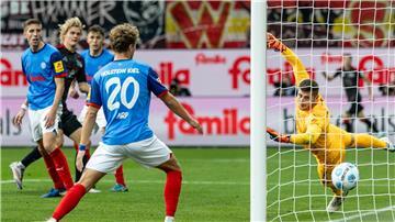 Union Berlins Tom Rothe (2. v l) trifft zum 0:2 gegen Kiels Torwart Timon Weiner (r).