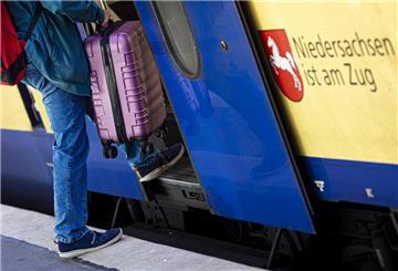 Ein Mann betritt im Hauptbahnhof Hannover mit einem Koffer eine Regionalbahn.