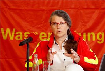 Eine Frau steht hinter einem Mikrofon und hält eine Rede.