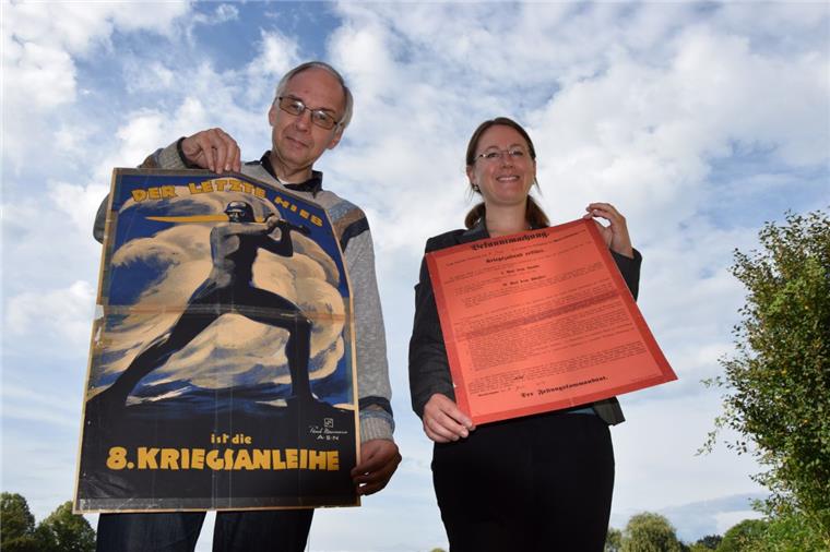 Kriegsverlauf spricht im Stadtarchiv aus Plakaten Uwe Jürgensen zeigt den Aufruf zur 8. Kriegsanleihe vom März 1918. Schlagzeile: „Der letzte Hieb“. Ein anderer Werbespruch, um mit Hilfe des Volkes die Kriegskasse zu füllen, lautete: „Gold gab ich für Eisen“. Dr. Julia Kahleyß hält die Bekanntmachung zum Kriegszustand vom 31. Juli 1914 in ihren Händen. Aufgerufen wird darin unter anderem, den vaterländischen Pflichten nachzukommen.