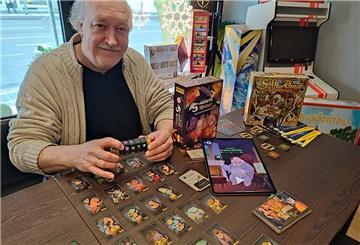 Ein Mann sitzt vor einem Spiel, das auf einem Tisch ausgebreitet ist.