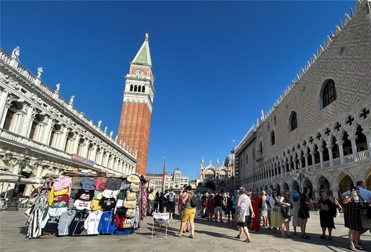 Touristen stehen auf dem Markusplatz in Venedig. 