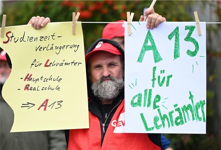 Ein Mitglied der Gewerkschaft Erziehung und Wissenschaft hält Plakate hoch.