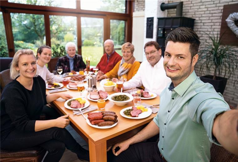Herzhaft geräucherte Pinkel Mitglieder der Familie Mühlenbeck haben sich zum Grünkohl-Essen an einem Tisch versammelt.