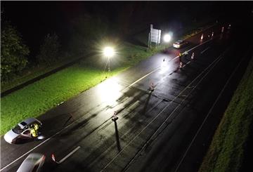 Blick von oben auf eine nasse Straße in der Dunkelheit, Lichtmast.