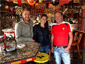 Verrückt nach Meer? Verrückt nach Ferrari! Das TV-Protagonisten-Pärchen der ARD-Serie, Jonas Dülberg und Indra Uihlein, haben wie schon so viele Gäste Münzen auf den Tisch der Kultkneipe geklebt. Inhaber ist Hans „Hansi“ Sauerbrei (rechts). Bayerischer Rundfunk/Farah M’haimdat.