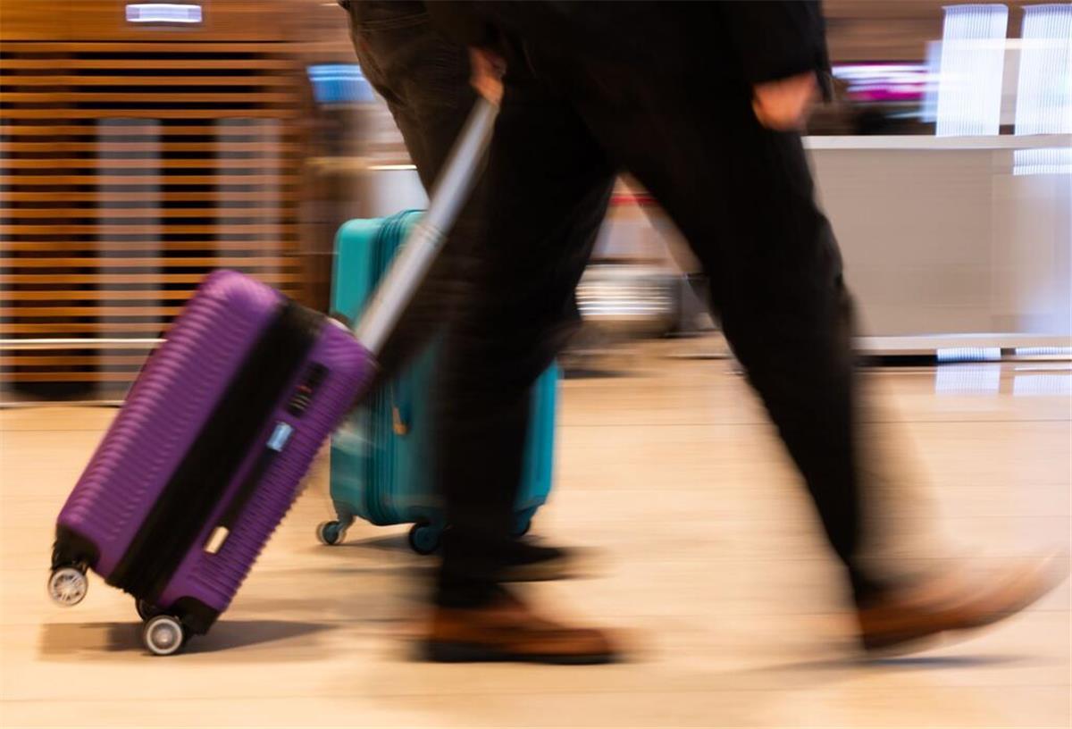 Urlaub geplatzt? So holt ihr euch mit der richtigen Versicherung euer Geld zurück Menschen gehen im Terminal 1 am Flughafen Berlin Brandenburg mit Gepäck durch die Haupthalle.