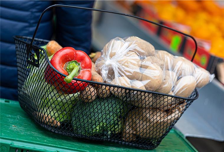Verbände fordern Abschaffung der Mehrwertsteuer auf Lebensmittel Der mit Paprika, Broccoli, Kartoffeln und anderen Lebensmitteln gefüllte Korb einer Kundin steht auf einer Kiste an einem Stand auf einem Wochenmarkt.