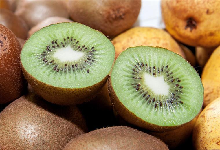 Kiwis und Granatäpfel liegen zusammen auf einem Tisch.