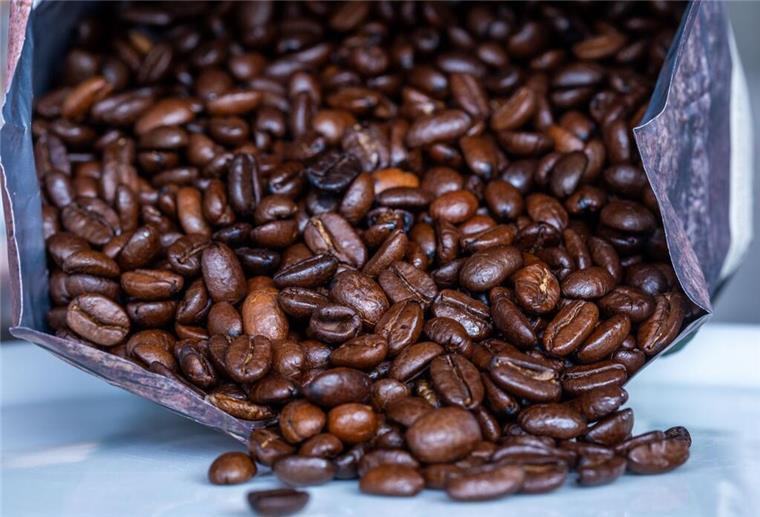 Kaffeehersteller schlägt Alarm! Preise steigen weiter, Verbrauch bleibt hoch Geröstete Kaffeebohnen liegen vor einer Tüte