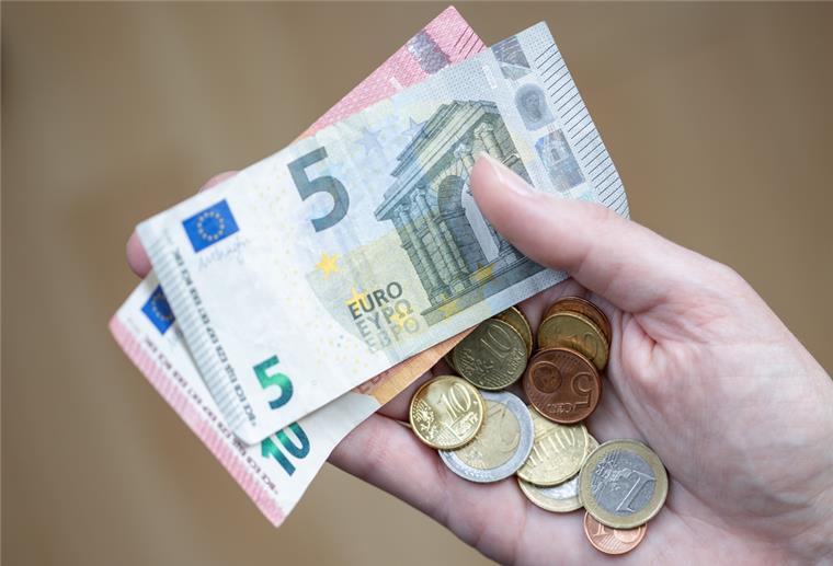 Umfrage: 40 Prozent sparen höchstens 100 Euro im Monat Eine Frau hält Geldscheine und Münzen in der Hand.