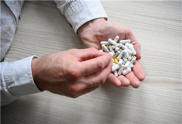 Eine Männerhand mit einer weißen Pille, dahinter eine zweite Hand gefüllt mit Tabletten.