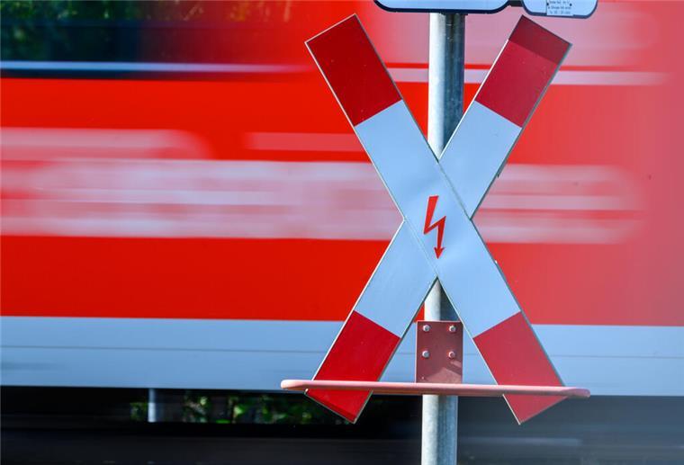 Bahnübergänge in Loxstedt werden gesperrt Ein Andreaskreuz an einem Bahnübergang. Im Hintergrund fährt ein Zug vorbei.