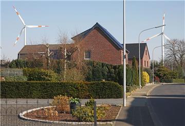 Windräder einer Windenergieanlage drehen sich im Windpark hinter Wohnhäusern in Heinsberg-Straeten. 