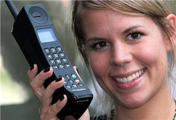 Eine Frau hält ein altes Mobiltelefon in der Hand.
