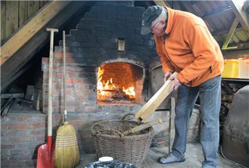 Vorheizen muss sein, um den Winter aus dem Steinbackofen zu vertreiben. Das Feuer knistert munter, und Gerhard Lohse legt noch einige Hölzer nach.